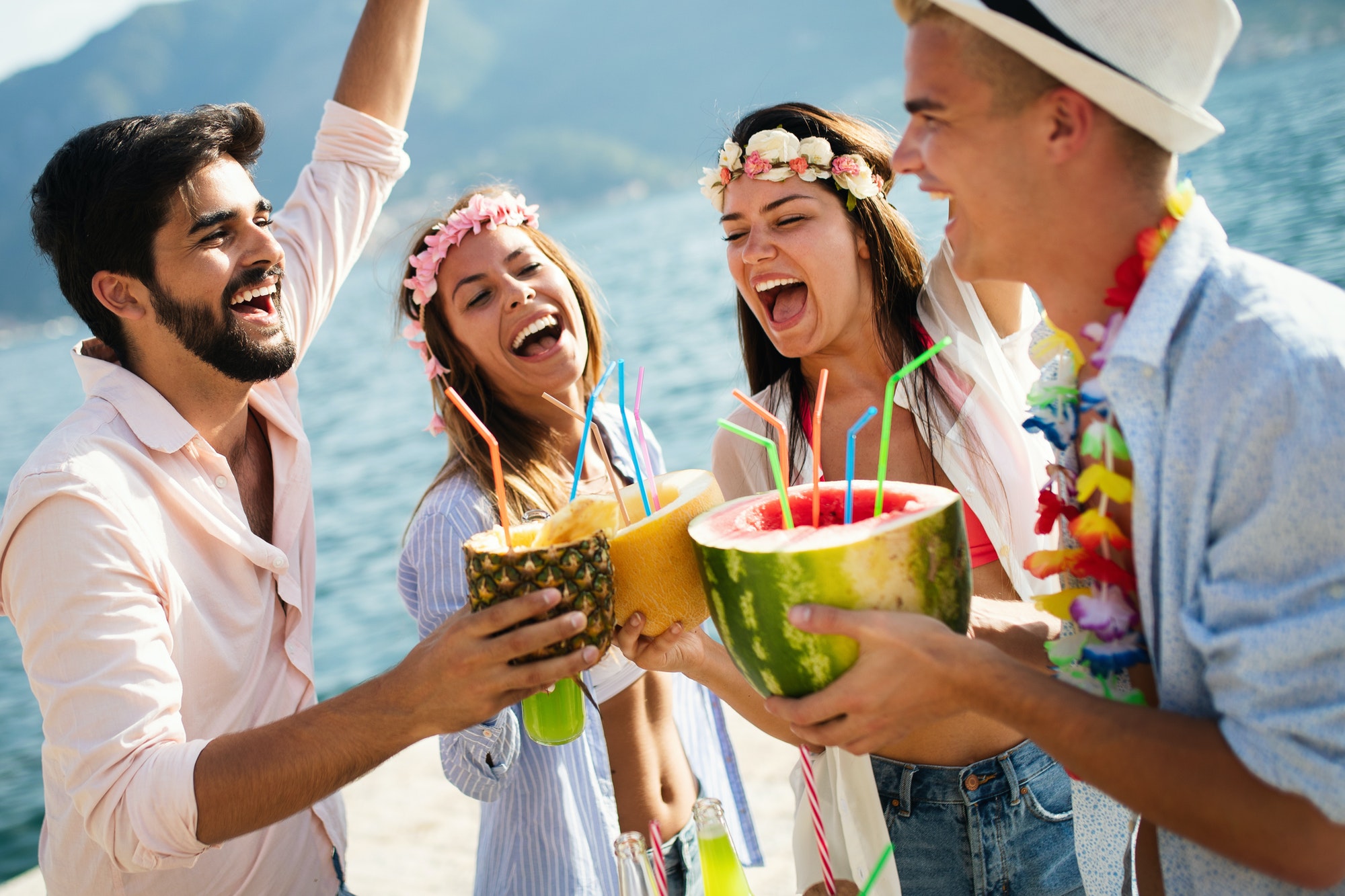 Young group of friends enjoying summer on the beach at sunset